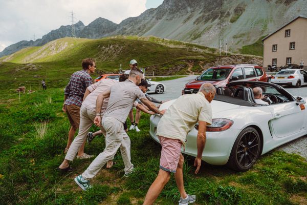 everybody helps push a car off the grass on the Albula pass in Switzerland